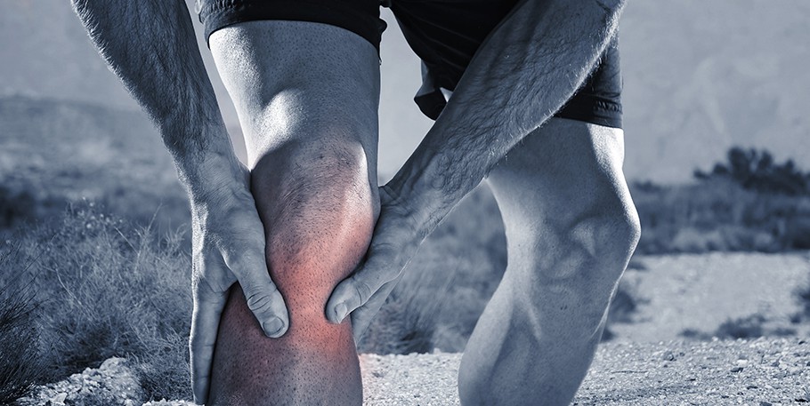 Fitmyrun articulation douleurs: young sport man with athletic legs holding knee in pain sufferin